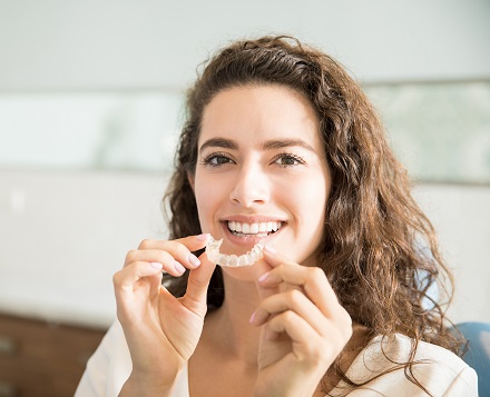 Beautiful Patient Holding Orthodontic Retainers In Dental Clinic